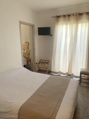 a bedroom with a large white bed and a window at Hôtel Beau Soleil in Le Lavandou