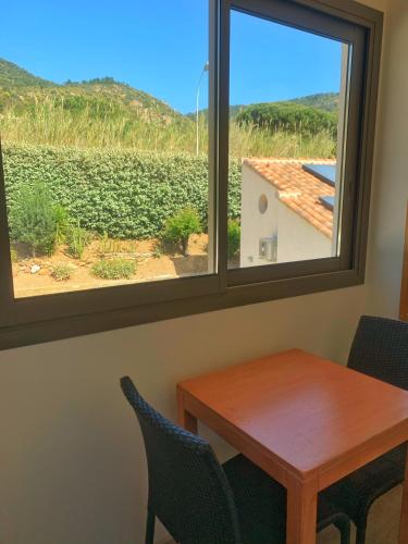 a table and chairs and a window with a view of a vineyard at Hôtel Beau Soleil in Le Lavandou