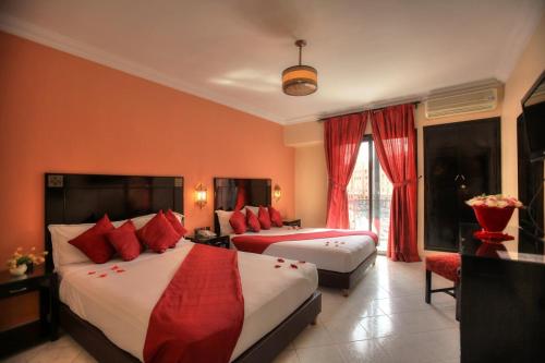 um quarto de hotel com duas camas com almofadas vermelhas em Mont Gueliz em Marrakech