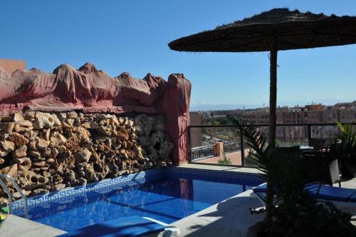 a swimming pool with a stone wall and an umbrella at Mont Gueliz in Marrakech