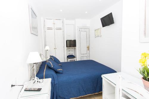 um quarto com uma cama azul num quarto branco em Hostal La Estrella em Marbella