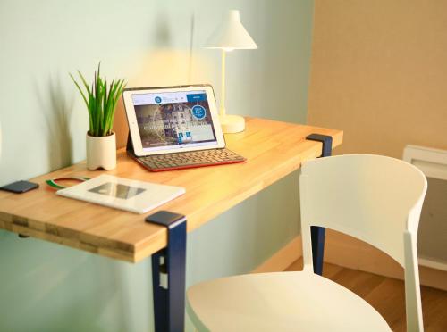 a laptop computer sitting on top of a wooden desk at Logis Hôtel Marguerite d'Anjou in Angers