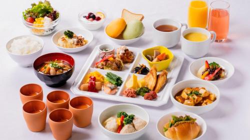 a white table topped with bowls and plates of food at KOKO HOTEL Hidatakayama - formaly Hotel Wing Hida Takayama in Takayama