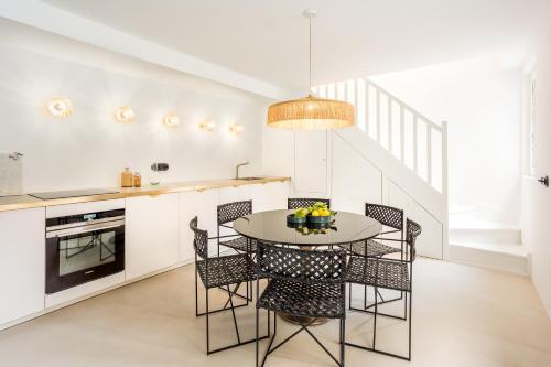 une cuisine blanche avec une table et des chaises dans l'établissement Habitat Parisien - Louvre Rivoli, à Paris