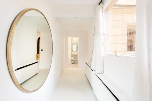 un miroir dans un couloir avec un mur blanc dans l'établissement Habitat Parisien - Louvre Rivoli, à Paris