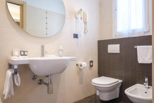 a bathroom with a sink and a toilet and a mirror at Hotel Touring in Bologna