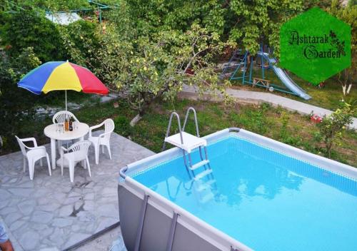 a patio with a table and an umbrella next to a pool at Ashtarak Garden GuestHouse in Ashtarak