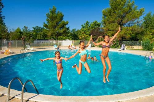 3 filles sautant dans une piscine dans l'établissement Mobile home tout confort Alexandre, à La Roque-dʼAnthéron