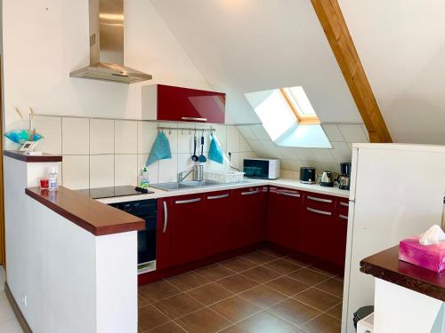 Elle comprend une petite cuisine avec des placards rouges et une fenêtre. dans l'établissement Le Paraty - Maison indépendante 72 m2, à Pont-Sainte-Maxence