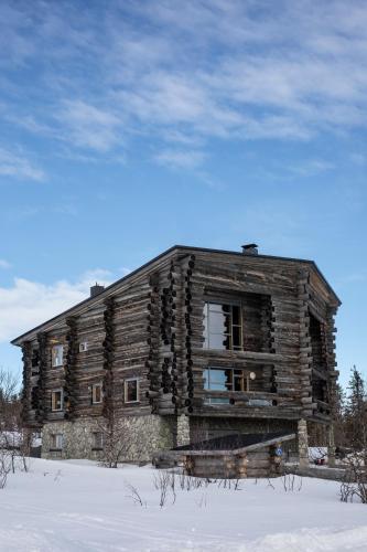 an old log cabin sitting in the snow at Santa's Villa Laavu in Kittilä