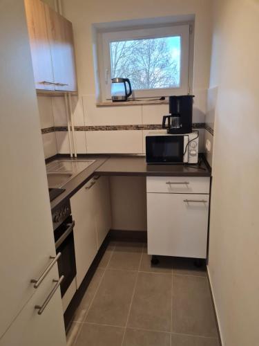 a small kitchen with white cabinets and a window at Wohnen im Grünen 2 in Heiligenstedten