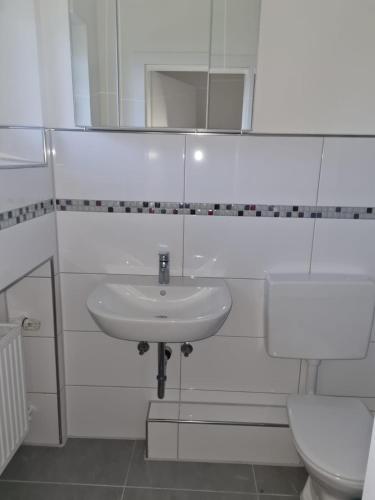 a white bathroom with a sink and a toilet at Wohnen im Grünen 2 in Heiligenstedten