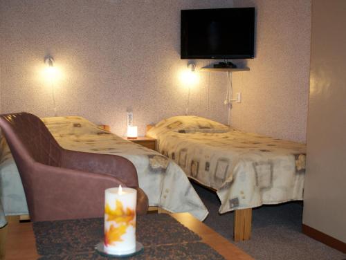 a hotel room with two beds and a candle on a table at Nooruse Majutus in Kuressaare