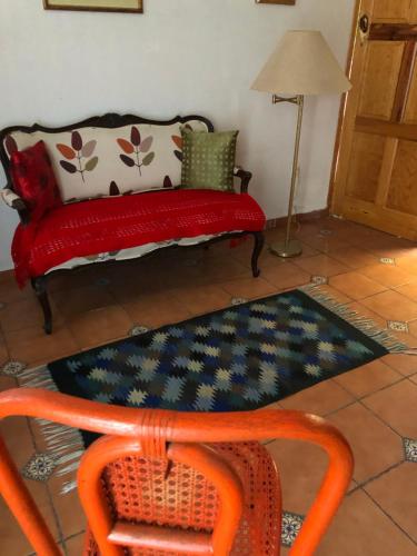 a red couch sitting in a living room with a rug at Maria Del Alma House in Mexico City