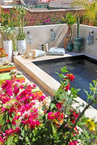 a garden with a pool with flowers and plants at Dar Kandi in Marrakech