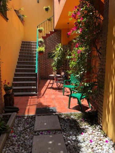 a courtyard with two chairs and stairs with flowers at Maria Del Alma House in Mexico City