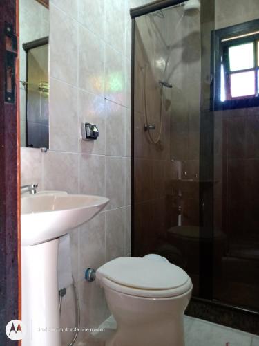 a bathroom with a toilet and a sink and a shower at Pousada Nova Conquista in Penedo