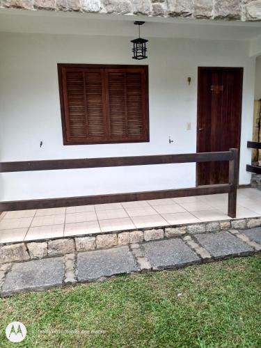 a white building with a wooden door and a porch at Pousada Nova Conquista in Penedo