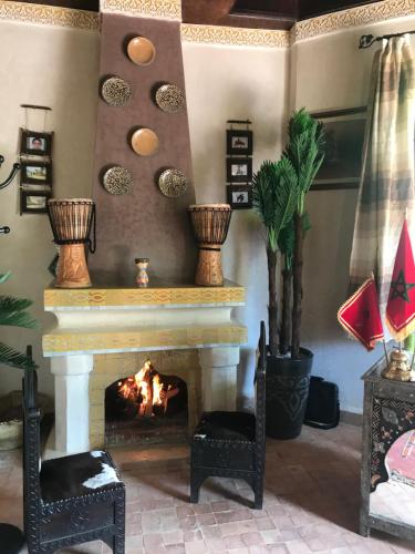 a living room with a fireplace and two chairs at Les Jardins de Ryad Bahia in Meknès