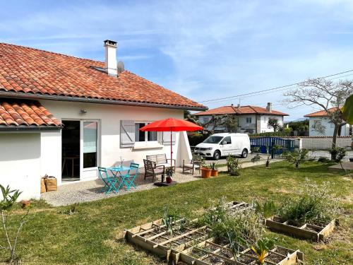 una casa blanca con un paraguas rojo y un patio en STUDIO, UN HAVRE DE PAIX - BIDART ERRETEGIA, en Bidart