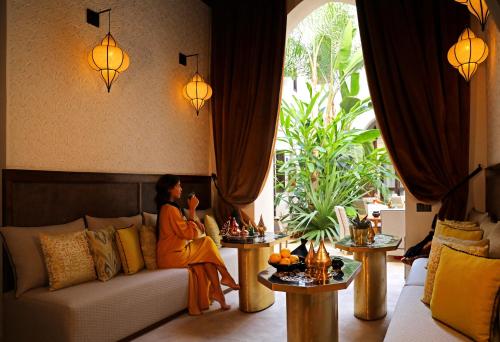 a woman sitting on a couch in a living room at Dar Kandi in Marrakech