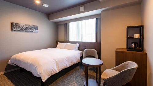 a hotel room with a bed and two chairs at KOKO HOTEL Hidatakayama - formaly Hotel Wing Hida Takayama in Takayama