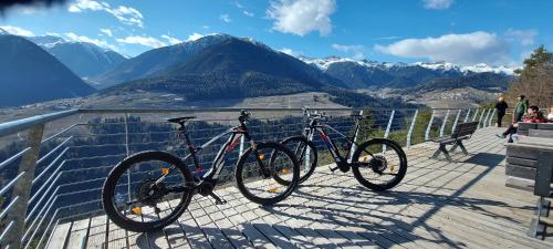 two bikes parked on a boardwalk with a view of mountains at Alpen Garten Hotel Margherita in Rumo