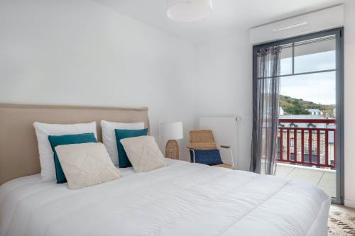 une chambre avec un grand lit blanc et un balcon dans l'établissement Appartement en bord de mer à Pléneuf-Val-André, à Pléneuf-Val-André