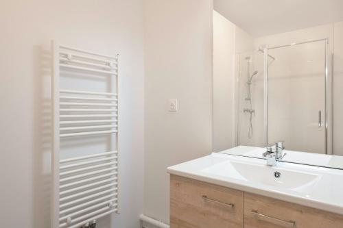 une salle de bain blanche avec un lavabo et une douche dans l'établissement Appartement en bord de mer à Pléneuf-Val-André, à Pléneuf-Val-André