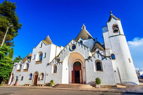a white church with a tower on a street at Dimora Palma in Alberobello