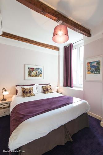 une chambre avec un grand lit avec une couverture violette dans l'établissement Hotel Villa La Tour, à Nice