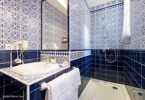 baño de azulejos azules con lavabo y bañera en Hotel Villa La Tour, en Niza
