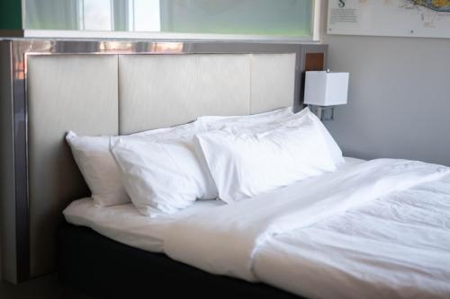 a bed with white sheets and pillows at River Sirens Hotel-Contactless Check in Hotel in Washington