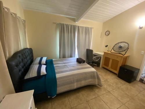 een slaapkamer met een bed, een bureau en een ventilator bij Casa Tranquila in Santa Ana