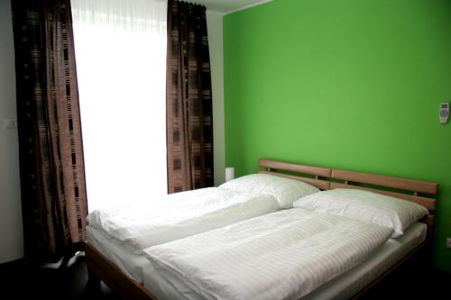 łóżko w zielonej sypialni z oknem w obiekcie Fine Restaurant & Apartments w mieście Malacky