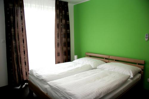 Bett in einem grünen Schlafzimmer mit Fenster in der Unterkunft Fine Restaurant & Apartments in Malacky