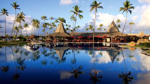 una piscina en un complejo con palmeras y edificios en Vila Galé Resort Marés - All Inclusive, en Guarajuba