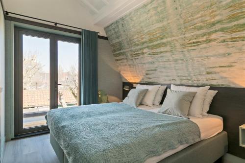 a bedroom with a large bed and a large window at DRL45 Luxury apartment in the heart of Domburg in Domburg