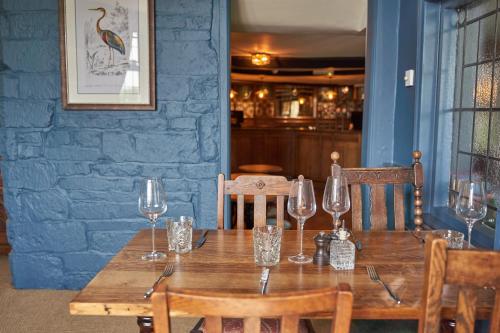 a wooden table in a restaurant with wine glasses at Beckford Inn in Beckford