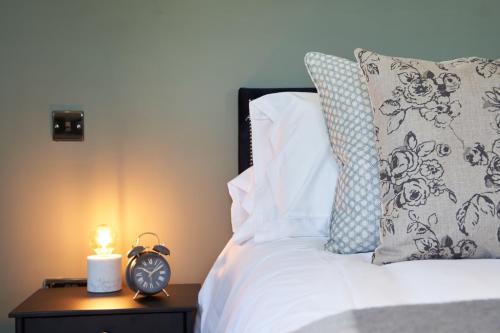 a bed with a night stand with a clock on it at Beckford Inn in Beckford
