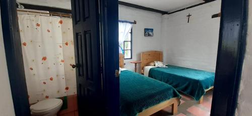 a small room with two beds and a toilet at Hostería Chíguac in Machachi