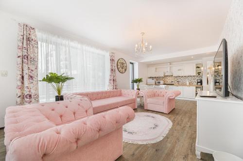 a living room with pink furniture and a kitchen at English Home in Silver Mountain Resort Poiana Brasov in Poiana Brasov
