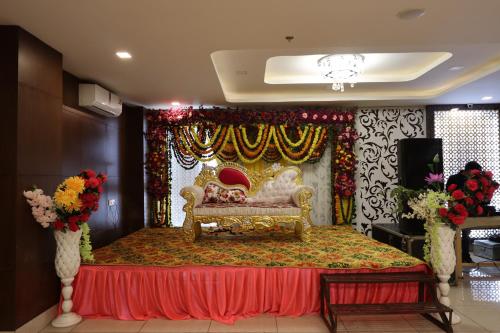 a room with a stage with a couch and flowers at Royal Mansion in Kulu