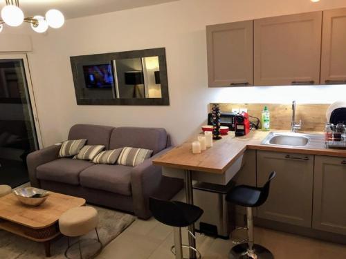 キャヴァレール・シュル・メールにあるModerne T2 avec garage ,très calme avec jardin privé et piscine, à 400m du centre ville et des plages, WIFI remise supplémentaire de 10 pourcent pour une location à la semaineのソファとテーブルのあるキッチンとリビングルーム
