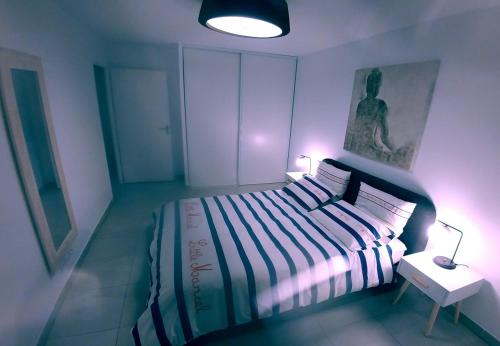 キャヴァレール・シュル・メールにあるModerne T2 avec garage ,très calme avec jardin privé et piscine, à 400m du centre ville et des plages, WIFI remise supplémentaire de 10 pourcent pour une location à la semaineのベッドルーム1室(大型ベッド1台、テーブル上のランプ付)