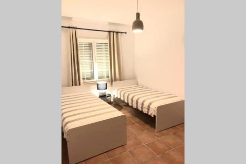 two beds in a room with a window at Vila Nova de Santa Susana - Resort in Alcácer do Sal