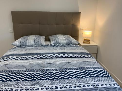 - un lit avec une couverture bleue et blanche et une lampe dans l'établissement Nanterre Room, à Nanterre