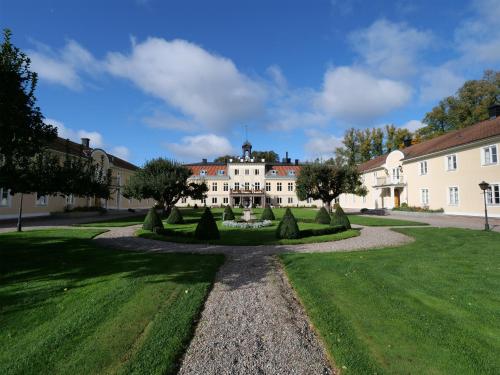 a large white building with trees in a yard at Södertuna Slott in Gnesta