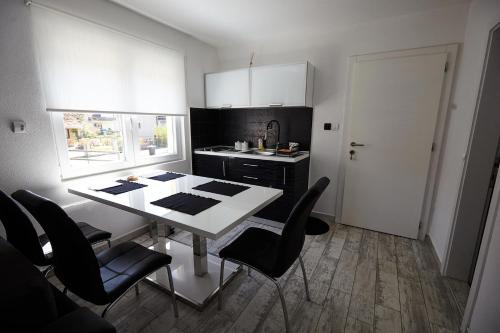 a kitchen with a white table and black cabinets at Apartment Azulmburgo in Vrnjačka Banja