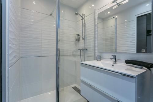 une salle de bain blanche avec une douche et un lavabo dans l'établissement Le Nude - Port Ambonne Village Naturiste, au Cap d'Agde